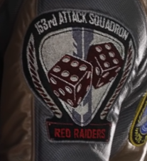A military style patch. Two red dice showing a pair of sixes sit between two red laurel wreaths. At the top are the words 153rd Attack Squadron. At the bottom are the words "Red Raiders".